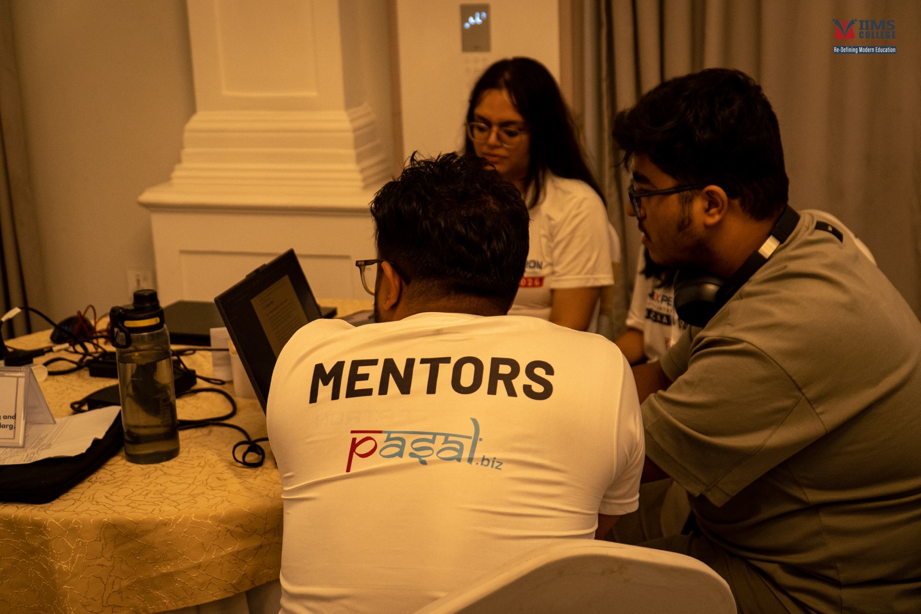 A mentor and participants reviewing technical work together on a laptop